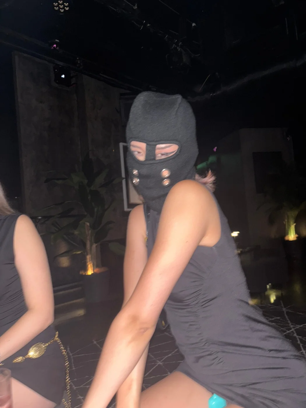 Lena in a black balaclava at a club night — no polish, just the moment