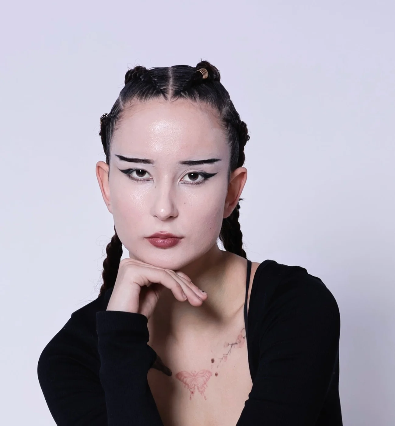 Portrait of Lena: graphic eyeliner, braided hair, butterfly tattoo — her signature look